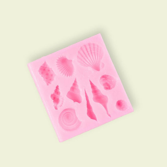 A pink silicone mold with various seashell shapes for food decoration.